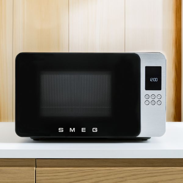 SMEG countertop microwave set in a black setting.